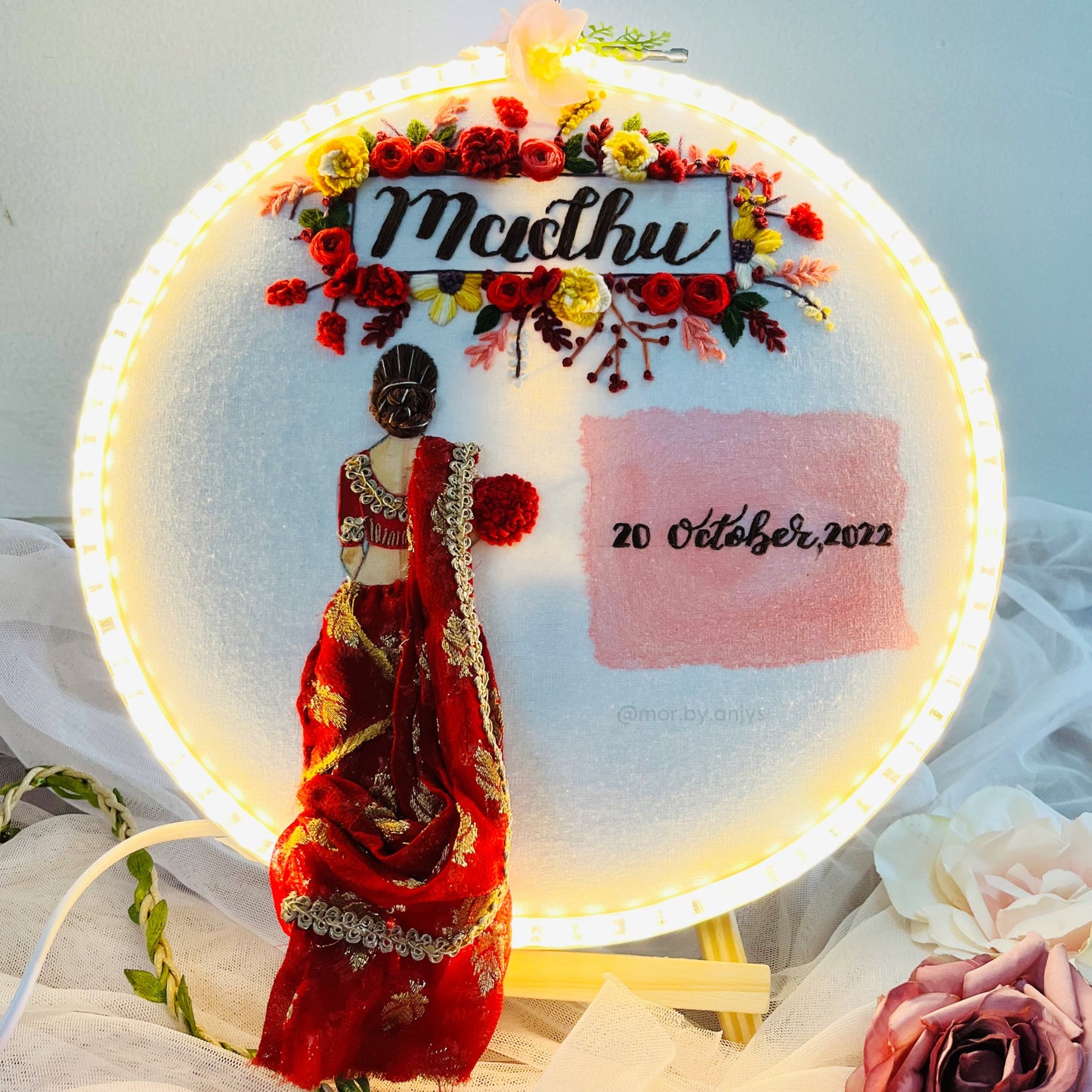 Decorative piece with a woman in a red saree, flowers, and text on a white background
