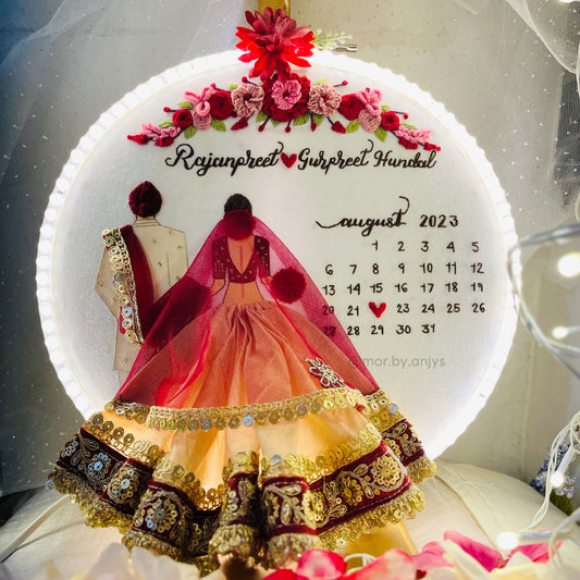 Decorative calendar with a couple in traditional attire and floral design, featuring the name on a white background.
